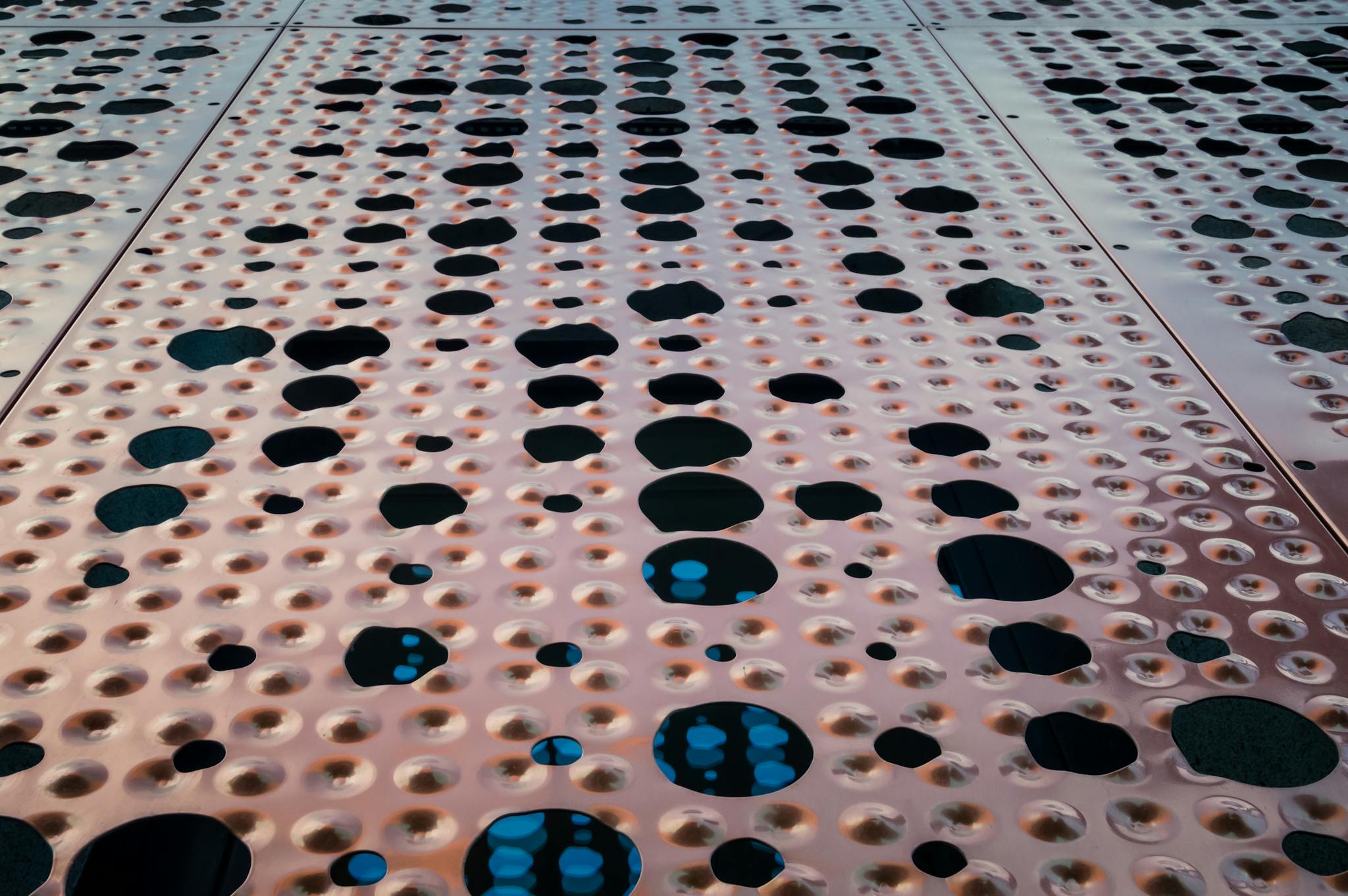 Abstract close-up of a perforated metal surface with geometric patterns and texture.