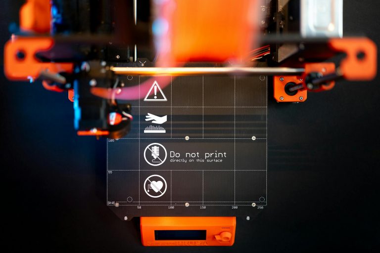 Detailed image of a 3D printer with caution signage, showcasing advanced manufacturing.